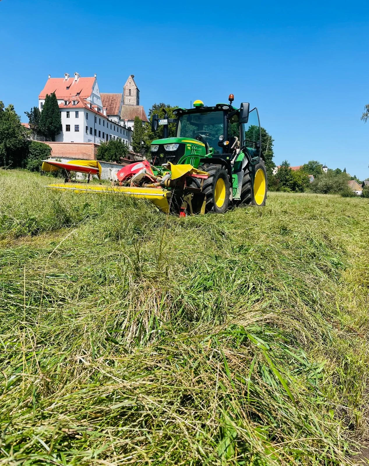 Mäharbeiten auf einer Wiese vor dem Ort